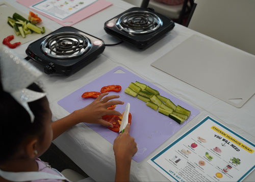 Little girl cutting up vegetables
