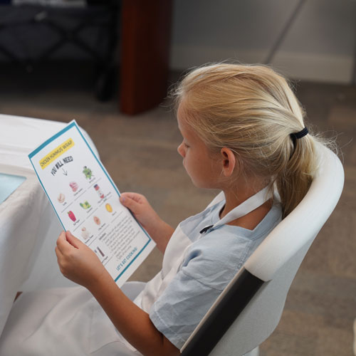 Young blond girl holding recipe and instructions for the Kids Kitchen Academy class